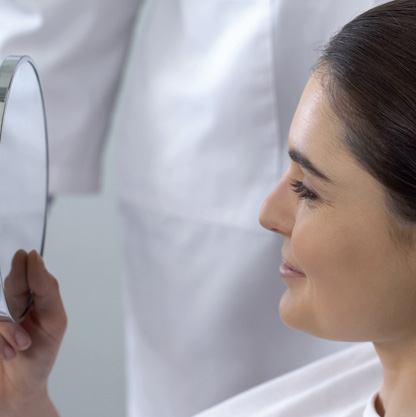 female-looking-in-mirror-after-cosmetic-procedure