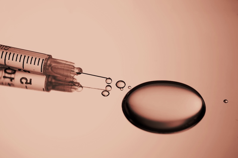 syringe-with-a-drop-of-drug-on-a-stainless-steel-background