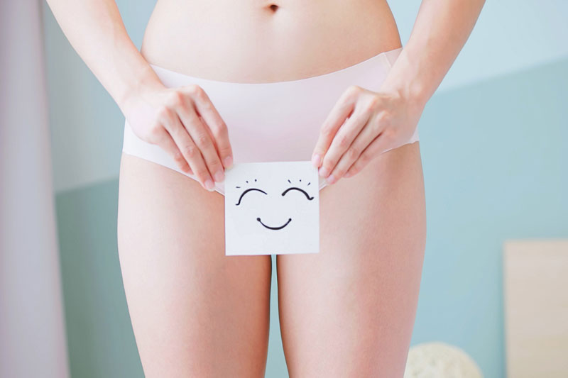 woman-holding-a-card-with-a-smiling-face-in-front-of-her-lower-abdomen
