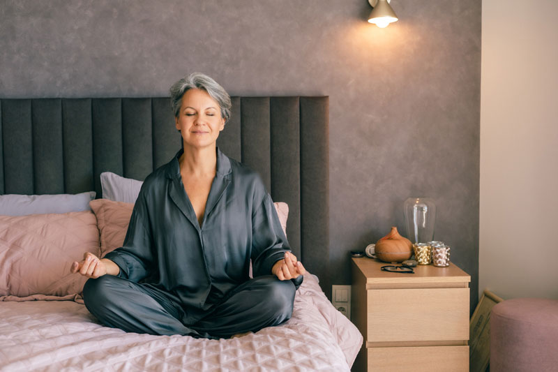woman-sitting-cross-legged-on-a-bed-in-a-dim-bedroom